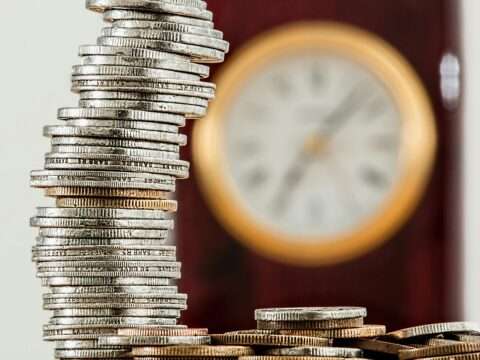 Coins lined up in front of a clock symbolizing business cash flow and time management in Canada.