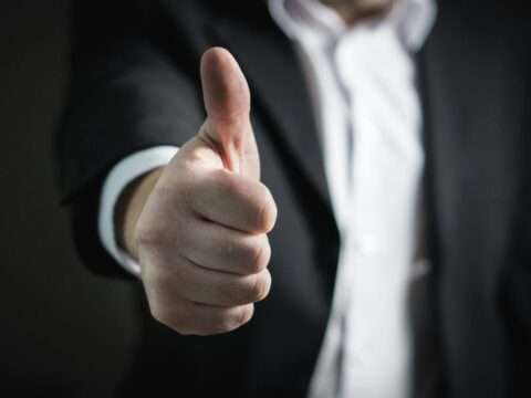 Man giving a thumbs up while submitting a business loan application online.