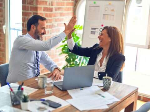 A man and woman high fiving after a successful loan application.