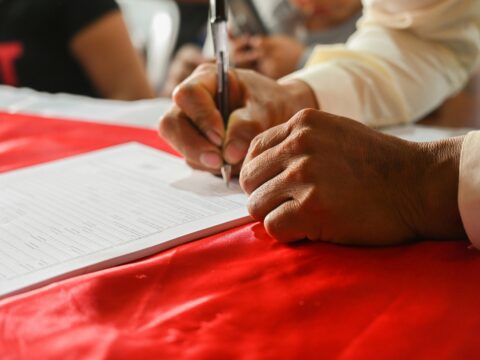Person signing paperwork for a small business loan application.